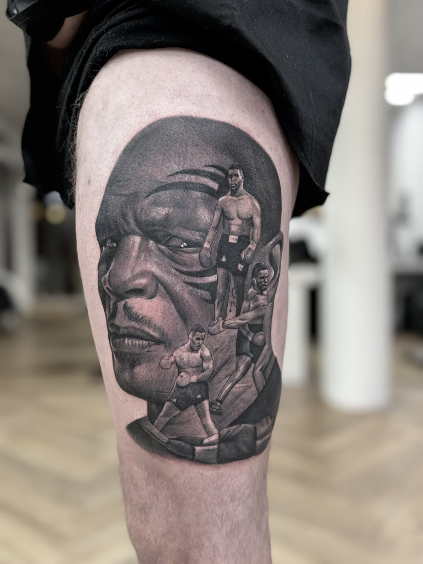 Portrait of a boxing legend with three smaller fighters in front of it, on the thigh