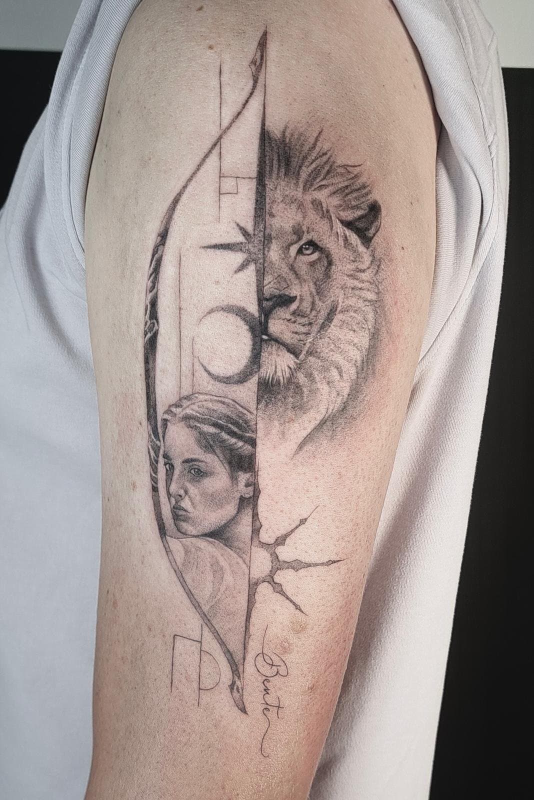 A lion and a woman's portrait in one design, split by a vertical line, on the upper arm